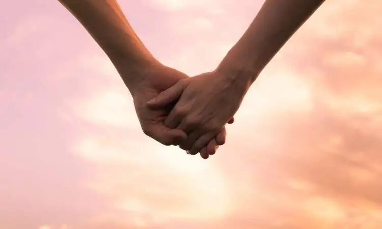due mani che si stringono al tramonto