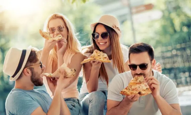 un gruppo di amici mangia insieme una pizza