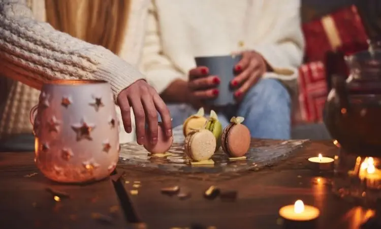 persone mangiano dei macarons su un tavolo addobbato per Natale