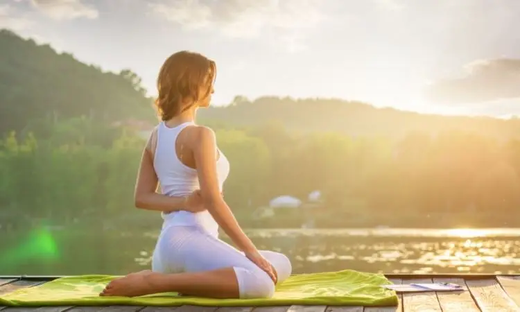 donna pratica yoga in riva a un lago al tramonto