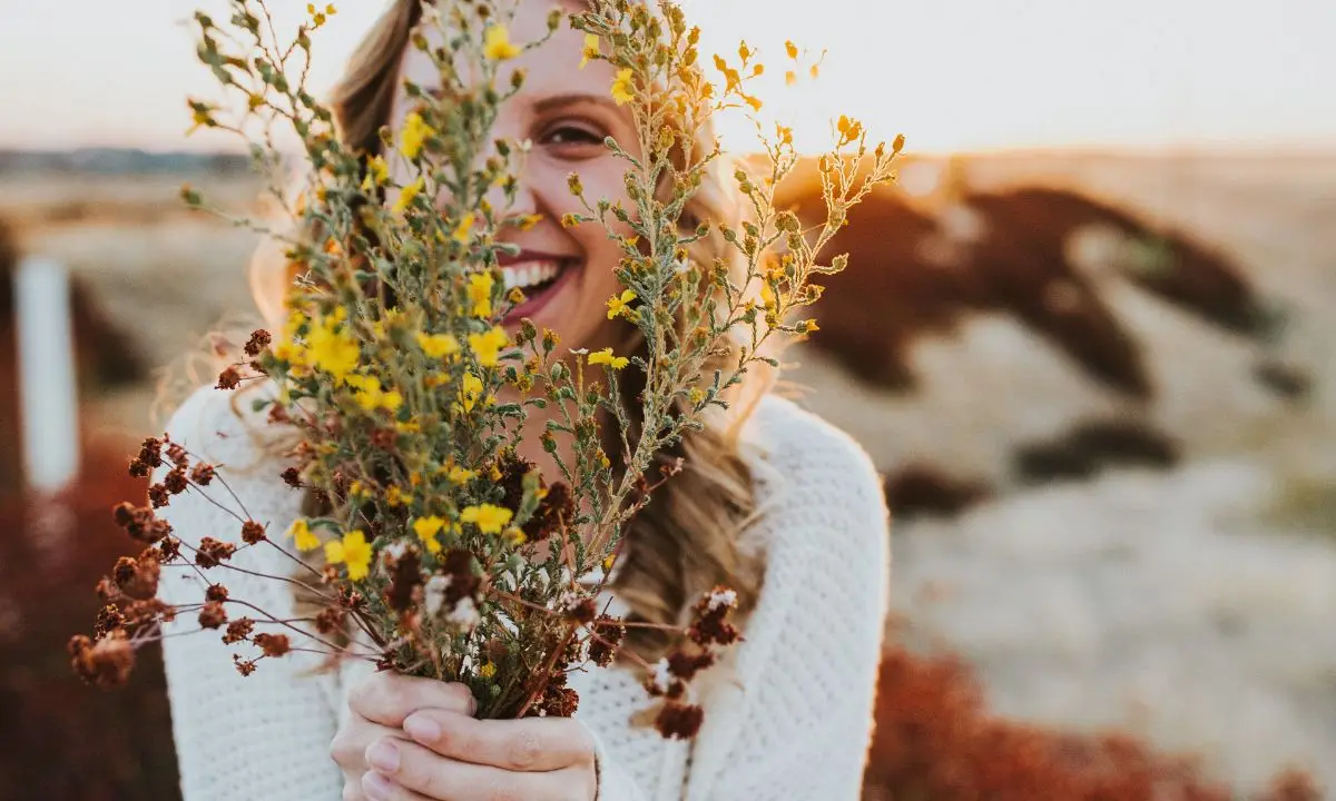 donna sorride reggendo un mazzo di fiori