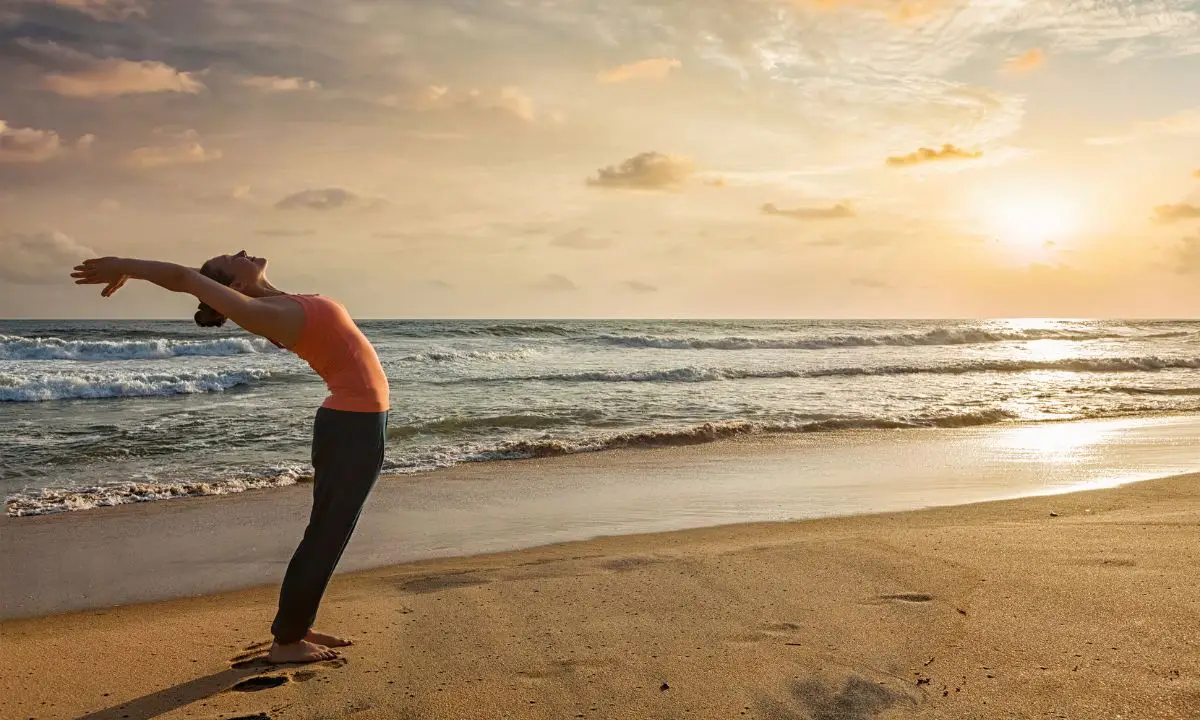 donna pratica lo yoga sivananda in spiaggia