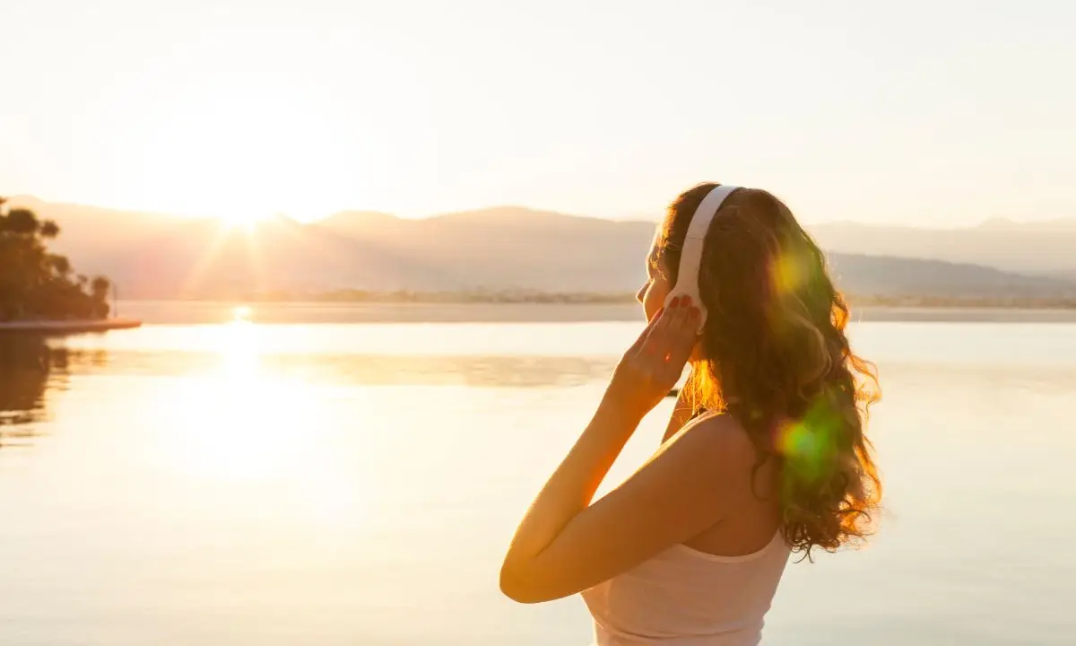 donna ascolta musica al tramonto con delle cuffie wireless