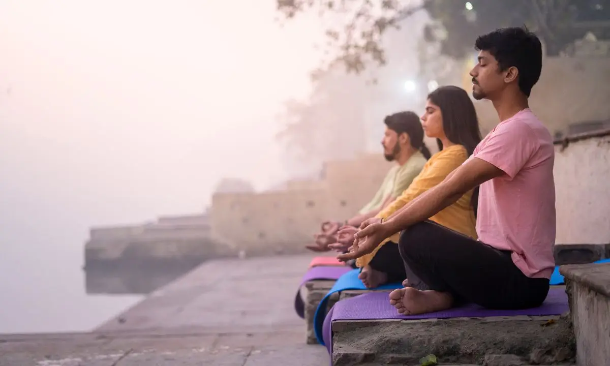 gruppo di persone di etnia indiana meditano in gruppo all'aperto