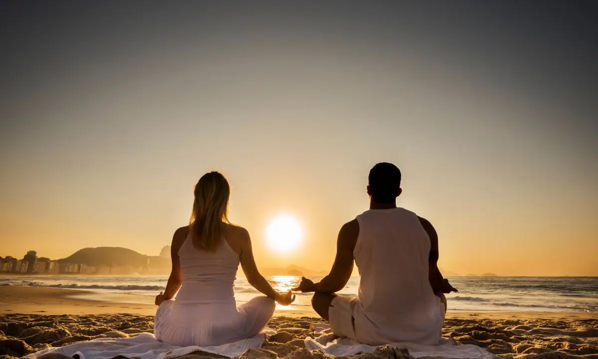 una coppia medita sulla spiaggia al tramonto