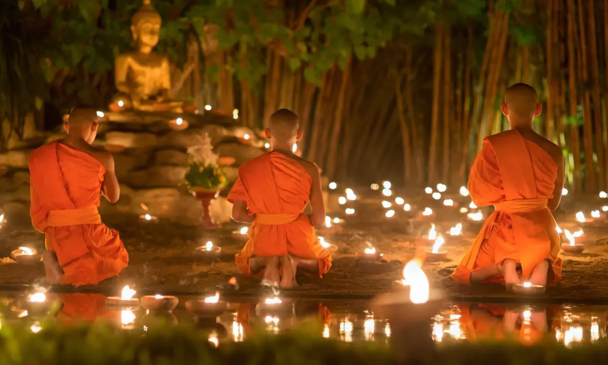 un gruppo di monaci medita davanti a una statua del buddha