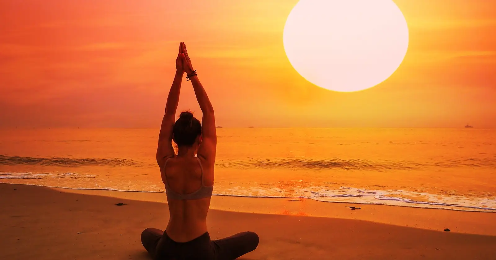 donna fa yoga in spiaggia al tramonto